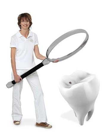 Esther Busch mit einer großen Lupe in der Hand und einem Zahn